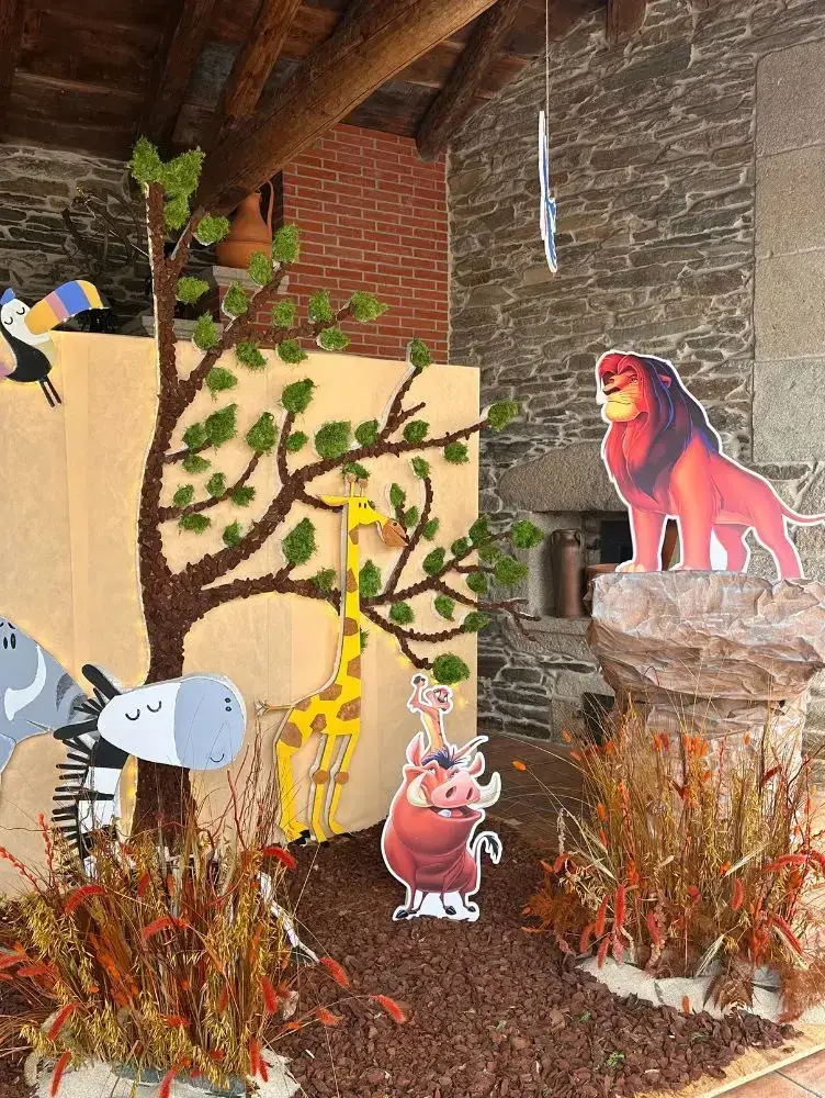 Decoración infantil con figuras de animais e tons cálidos, recuncho temático en evento familiar.