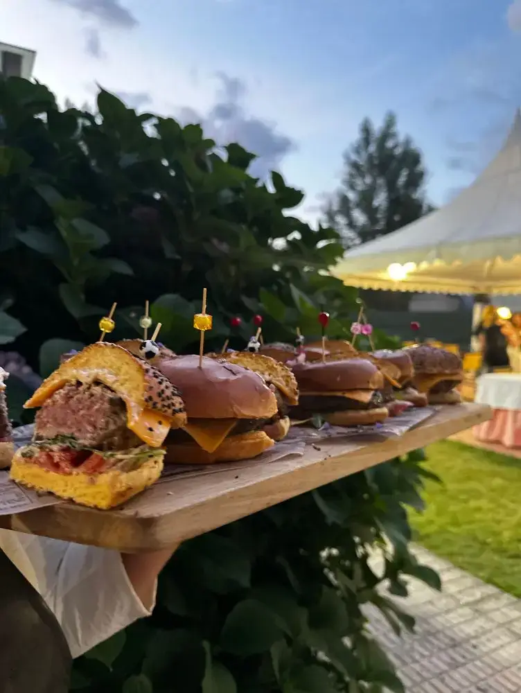 Mini hamburguesas gourmet ao aire libre con fondo verde, catering Cinza e Lume.